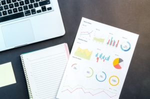 Laptop with note pad and data sheet on a desk 